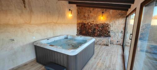 bañera de hidromasaje en una habitación con pared de piedra en Casas Rurales con Jacuzzi Quijote y Sancho en Ossa de Montiel