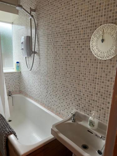 a bathroom with a white tub and a sink at Cosy cottage with a canal view in Hebden Bridge