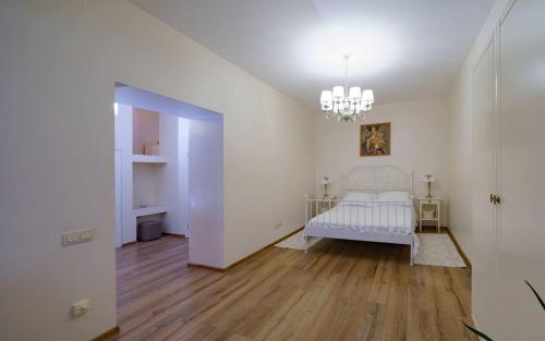 a white bedroom with a bed and a chandelier at Family apart in Odesa