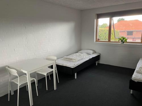 a room with a bed and a table and a window at Ebbesens Bed and Bath - two double rooms in Herning