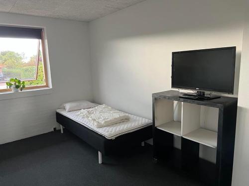 a room with a small bed and a television at Ebbesens Bed and Bath - two double rooms in Herning