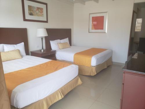 a hotel room with two beds and a television at Hotel Presidente in Ensenada