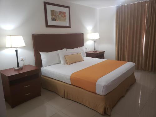 a bedroom with a large bed with two night stands and two lamps at Hotel Presidente in Ensenada