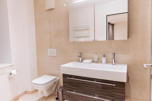 a bathroom with a sink and a toilet and a mirror at Montreux Grand Rue - Swiss Hotel Apartments in Montreux