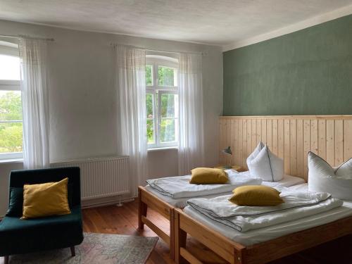 a bedroom with two beds and a chair and windows at Pasterhof Eichhorst in Friedland
