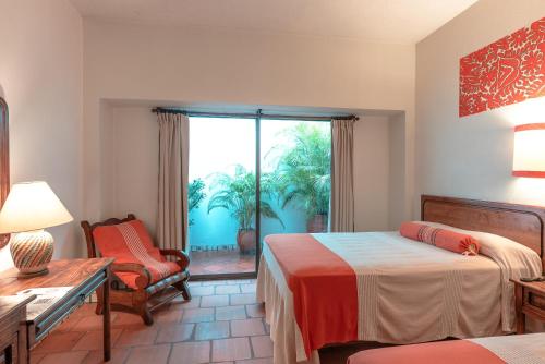 a bedroom with two beds and a chair and a window at Parador del Dominico in Oaxaca City