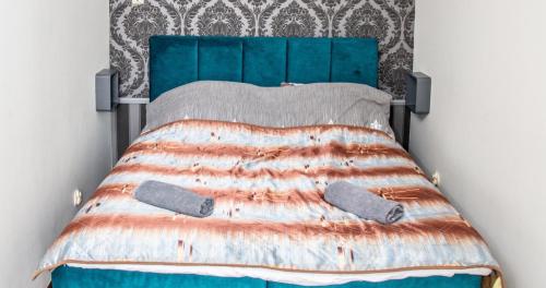 uma cama com uma cabeceira azul e dois pares de sapatos em Zachód Słońca Apartments em Mielno