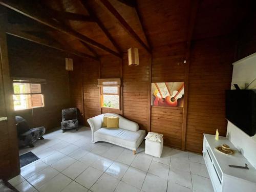 a living room with a white couch and a tv at Cabana com piscina - 5 min a pé da praia - Porto Belo in Porto Belo