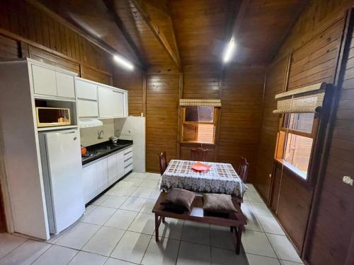 a kitchen with a table and a white refrigerator at Cabana com piscina - 5 min a pé da praia - Porto Belo in Porto Belo