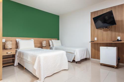 a hotel room with two beds and a flat screen tv at Costa do Sol Boutique Hotel in Búzios