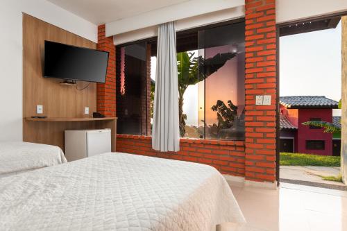 a bedroom with a bed and a large window at Costa do Sol Boutique Hotel in Búzios