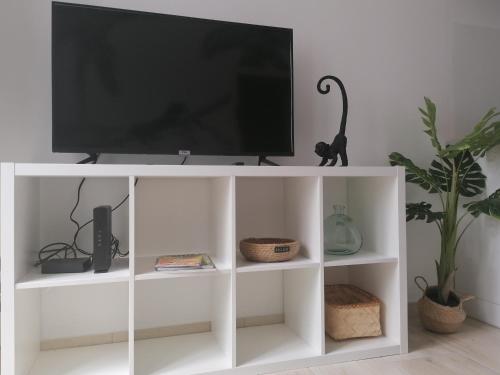 a white entertainment center with a television on top at Le manut, charme et confort in Dijon
