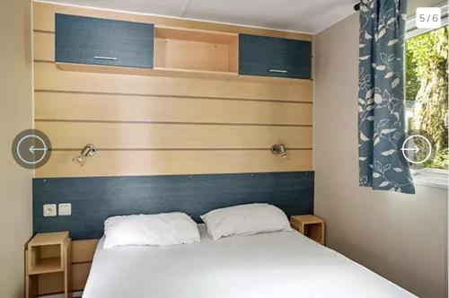 a bedroom with a white bed with a blue headboard at Mobil-Home Camping de la dune Blanche in Camiers