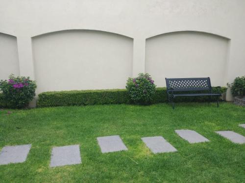a bench sitting in the grass next to a building at Estancia Santa Fe in Celaya