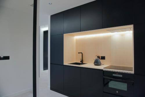 uma cozinha com armários pretos e um lavatório em Loft Mardevela em Sanxenxo