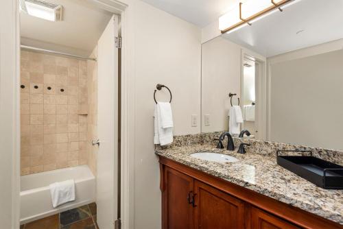 a bathroom with a sink and a mirror and a tub at Aspenwood by Snowmass Vacations in Snowmass Village