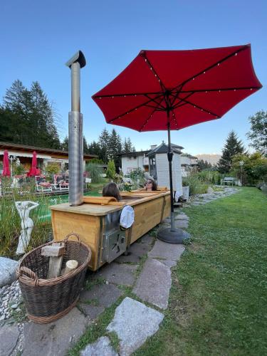 a red umbrella sitting next to a hot tub with a grill at Gästehaus Waldrand Garni in Wiesing