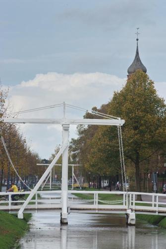 a white bridge in a park in the rain at Stoevchen Café Hotel in Papenburg