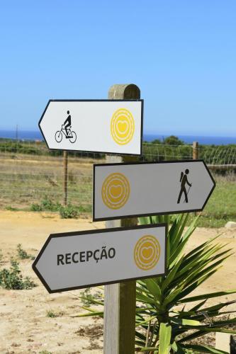 two signs on a pole with a person on a bike at Herdade Do Touril in Zambujeira do Mar