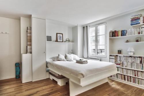 biała sypialnia z dużym łóżkiem i półkami na książki w obiekcie Large studio two steps to Vincennes Castle at the doors of Paris - Welkeys w mieście Vincennes