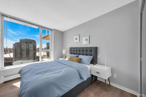 a bedroom with a bed and a large window at Spacious DT 2-BDR High-rise with view, pool, gym in Vancouver
