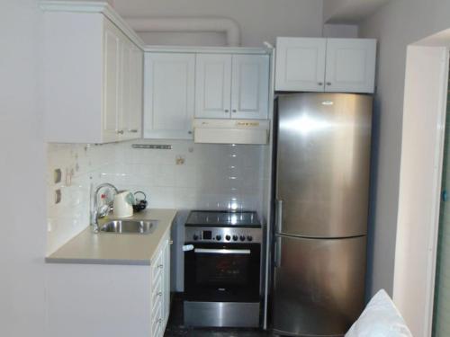 a kitchen with a stainless steel refrigerator and white cabinets at Lovingly restored apartment Galatsi in Athens