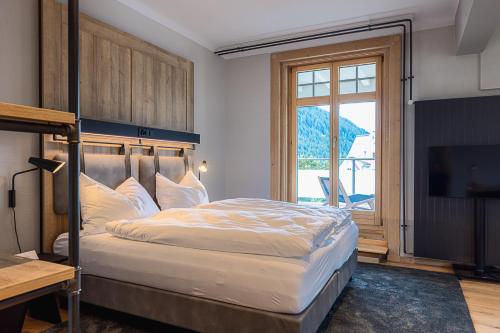 a bedroom with a large bed and a television at ALPINE INN Davos in Davos