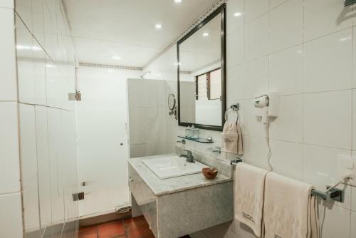 a white bathroom with a sink and a mirror at Parador del Dominico in Oaxaca City