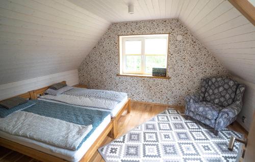 a bedroom with a bed and a chair in a attic at Vormsi Suvila in Hullo