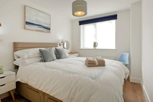 um quarto com uma cama grande com lençóis brancos e uma janela em Seaside Annexe em Felpham