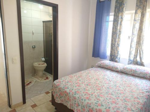 a bedroom with a bed and a bathroom with a toilet at Sobrado Lindóia in Curitiba