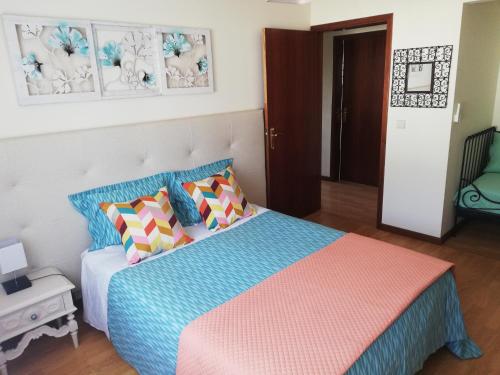 een slaapkamer met een bed met kleurrijke kussens bij Casinha de Nogueirinha in Macedo de Cavaleiros