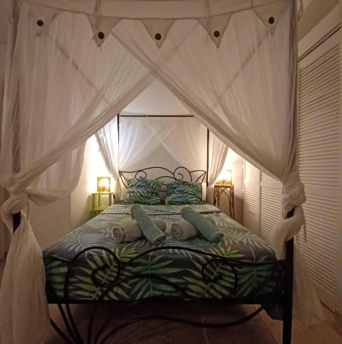 a bedroom with a canopy bed with pillows at Ti coin de paradis Ylang Ylang in Le Diamant