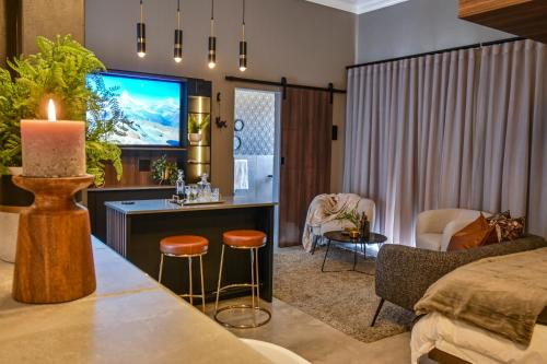 a living room with a tv and a couch and a table at Summer PALACE Guesthouse in Bloemfontein