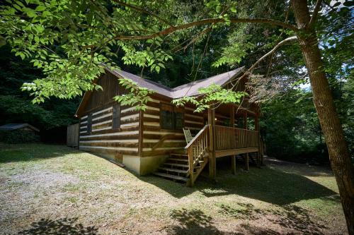 a log cabin with a staircase and a tree at A Cabin In The Woods in Pigeon Forge