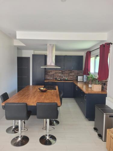 eine Küche mit einem Holztisch und schwarzen Schränken in der Unterkunft La maison des castors -1 flat and 1 studio in Bièvres