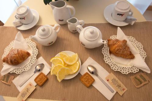 a table with plates of food and teapots and oranges at Lacroma Aparthotel in Grado