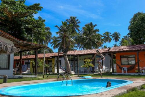 a woman standing in a swimming pool in front of a house at Chalés Praias Brasileiras in Maragogi