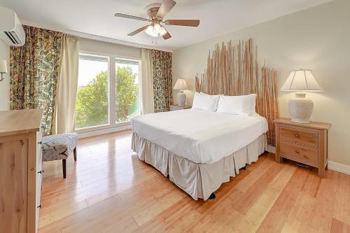 1 dormitorio con cama blanca y ventilador de techo en Aloha Condo en Padre Island