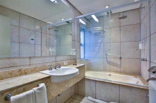 uma casa de banho com um lavatório, uma banheira e um espelho. em Hotel Transamerica Berrini em São Paulo