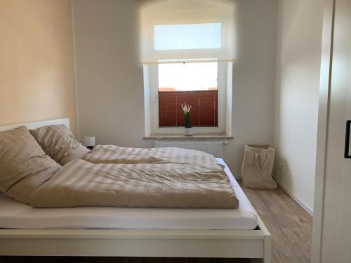 Cama en habitación con ventana en FEDDERSEN LIVING Moderne Ferienwohnungen - Gemütlich - Netflix - Voll ausgestattet - Waschmaschine - zentral gelegen, en Brunsbüttel