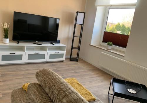 a living room with a television and a couch at FEDDERSEN LIVING Moderne Ferienwohnungen - Gemütlich - Netflix - Voll ausgestattet - Waschmaschine - zentral gelegen in Brunsbüttel