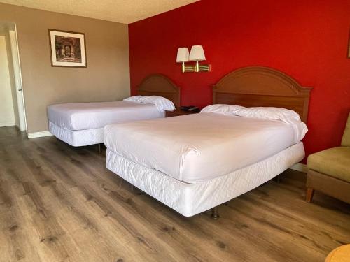 two beds in a hotel room with red walls at Travelodge by Wyndham Imperial - El Centro in El Centro