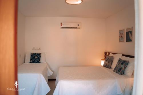 two beds in a room with white walls at Cores do Arraial Residence Hotel in Arraial d'Ajuda