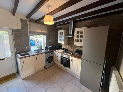 cocina con nevera, lavadora y secadora en Cosy cottage with beautiful mountain views en Blaenavon