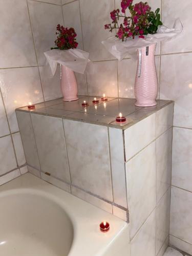 three vases with flowers on a shelf with candles at The Downtown Hotel in Soufrière