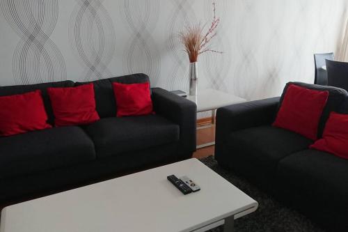 a living room with two black couches and red pillows at Elegante Flat en inmejorable ubicación - San Isidro in Lima