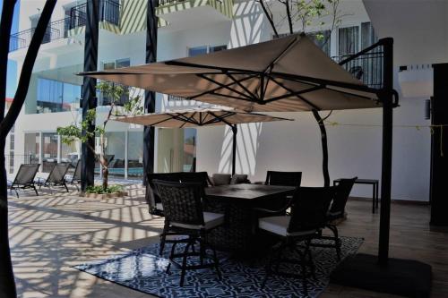 a table and chairs under an umbrella on a patio at Steps from the Beach Condo Life Bucerias Golden Zone in Bucerías