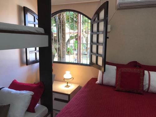um quarto com uma cama e uma grande janela em Suites Bouganville ( casa 2) em Porto de Galinhas