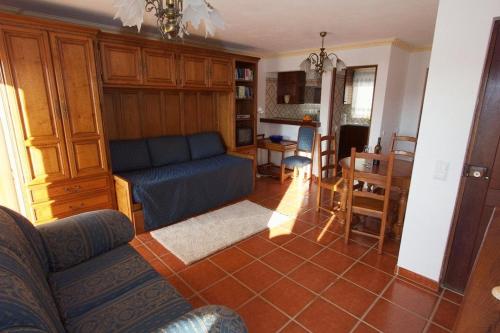 a living room with a blue couch and a kitchen at Apartamentos Os Descobrimentos in Burgau